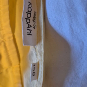 Gul klänning från Kappahl - Säljer en söt gul klänning från Kappahl i storlek 158. Klänningen har trekvartsärmar och knappar framtill. Perfekt för vår och sommar med sin ljusa och glada färg. Den har en lös passform som gör den bekväm att bära hela dagen.