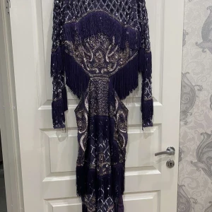 Festklänning  - Mörklila festklänning i storlek 40,köpt på ASOS,mycket bra skick har endast används 1 gång ,öppen vid midjan även slits på sidan ,dragkedja bak,hel utsmyckad 