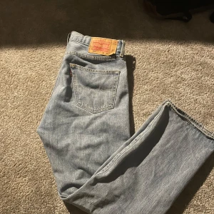 Levis jeans i ljusblå denim - Säljer ett par klassiska Levis jeans i ljusblå denim. De har en straight passform och är i bra skick. Perfekta för vardagsbruk och kan matchas med nästan vad som helst. Jag brukar vanligtvis ha 32/32 men dessa passade jättebra!