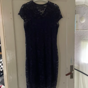 Mörkblå spetsklänning - Säljer en elegant mörkblå spetsklänning i storlek XXL. Klänningen har en vacker spetsdesign och korta ärmar. Perfekt för festliga tillfällen eller en utekväll. Den är i nyskick och redo att bäras av någon som vill känna sig extra fin!