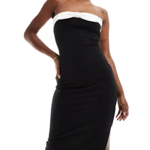 Svart axelbandslös klänning - Snygg svart axelbandslös klänning med vit rosett detalj upptill. Perfekt för festliga tillfällen. Klänningen är lång och har en elegant passform som framhäver figuren. 