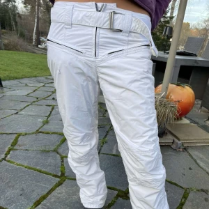 Vita byxor med bälte - Snygga vita byxor med hög midja och ett brett bälte. Byxorna har dragkedjedetaljer och en modern design som är perfekt för en trendig look. Så fina som passar alla överdelar. Perfekt till afterski  