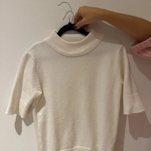 Vit stickad polotröja från Vila - Säljer en stilren vit stickad polotröja från Vila. Tröjan har korta ärmar och en ribbad polokrage som ger en klassisk look. Perfekt för att hålla sig varm och snygg under kyligare dagar. Passar bra till både jeans och kjol. 🧶✨