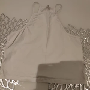 Vit linnetopp från NLY Trend - Säljer en stilren vit linnetopp från NLY Trend. Toppen har en enkel design med smala axelband och är perfekt för varma dagar. Passar bra till både jeans och kjol.
