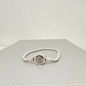 Pandora berlockarmband - Elegant silverfärgat berlock armband från pandora. Armbandet har ett dekorativt lås. Armbandet har en stilren design och passar perfekt för att ge en extra touch till din outfit eller ge bort i present. 