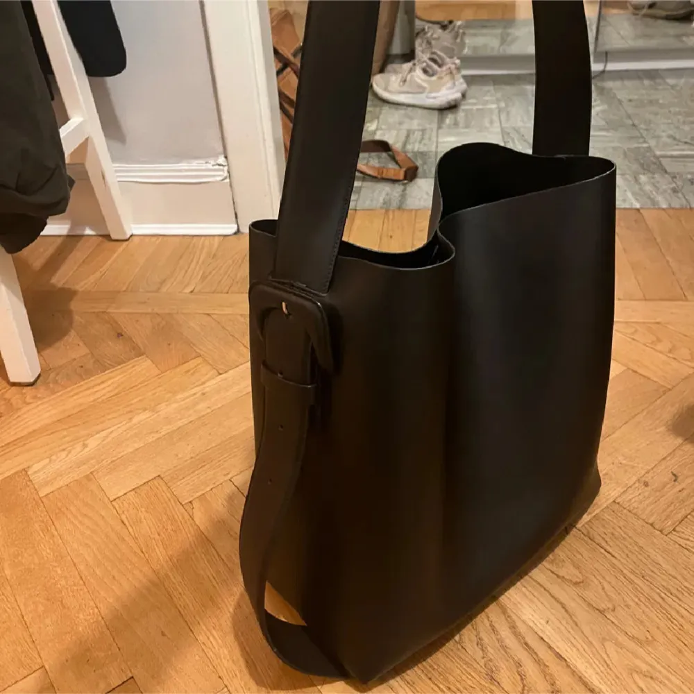 Toteväska  från ARKET. stor modell  Använd ett par gånger därav i mycket fint skick. Endast liten repa som inte syns på bild.  Mått 35 × 32 × 13 cm. Färg: svart. Nypris: 3290 kr.  Köparen står för frakt. Kan hämtas upp på Södermalm . Laukut & Käsilaukut.