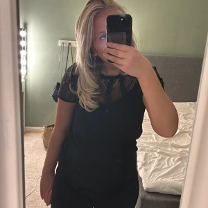 Svart blus med spetsdetaljer - Snygg svart blus. Säljer på grund av den inte kommer till användning. Använd 2 gånger.