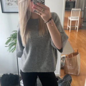Grå stickad tröja - Säljer en mysig grå stickad tröja med trekvartsärmar. Perfekt för kyligare dagar och enkel att matcha med olika outfits.