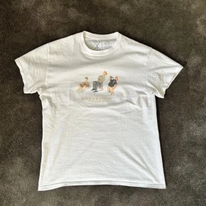 Vit t-shirt från Sour - Säljer en vit t-shirt från Southampton  med ett tryck av flera figurer på framsidan. T-shirten har en klassisk passform och är kortärmad. Perfekt för en avslappnad stil.