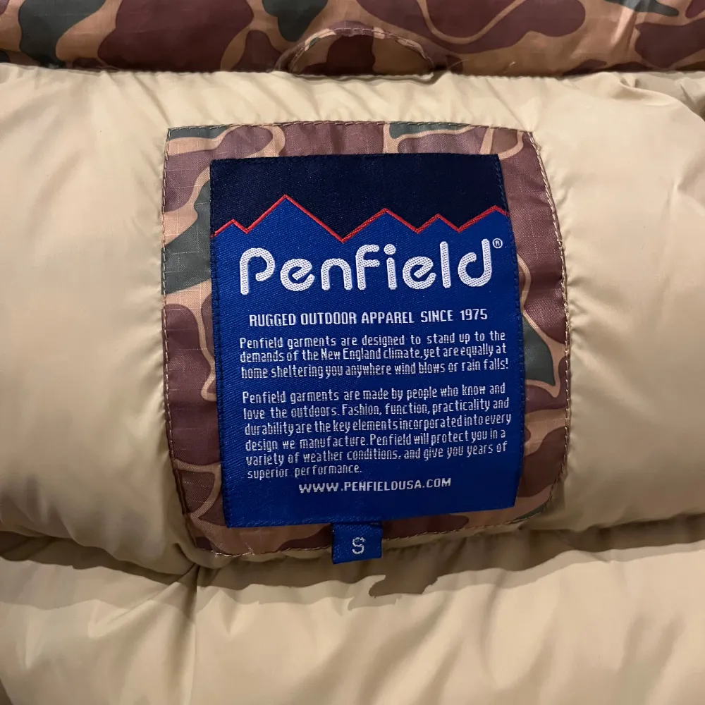 Säljer en cool camouflagefärgad dunväst från Penfield. Västen har ett klassiskt mönster i grönt och brunt med knappar framtill. Perfekt för utomhusaktiviteter och håller dig varm och stilren. Västen är i storlek S och i väldigt bra skick. Bara att höra av sig vid eventuella frågor! ☺️. Takit.