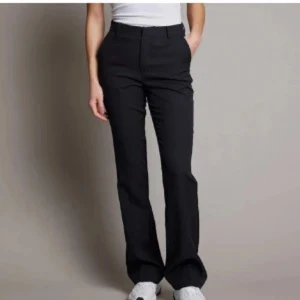 Svarta kostymbyxor - Snygga svarta kostymbyxor med hög midja och bootcut-stil. Perfekta för en stilren look. Kombinera med en enkel topp för en chic outfit.