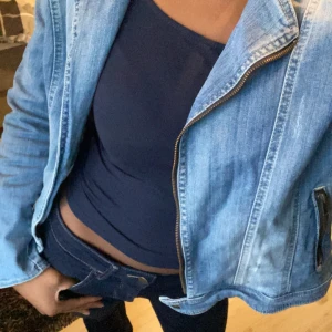Blå jeansjacka från KappAhl - Snygg blå jeansjacka från KappAhl med dragkedja framtill. Jackan har en klassisk design med långa ärmar och två fickor på sidorna. Perfekt för en avslappnad stil.