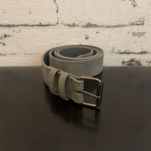 Grått mocha bälte - Snyggt grått bälte i mocka med ett stilrent silverfärgat spänne, 1 meter långt och har flera hål för att justera för din passform🙌Passar till finare tillfällen och även vardags och är perfekt för att komplettera din outfit🤩Kontakta mig om du är intresserad‼️
