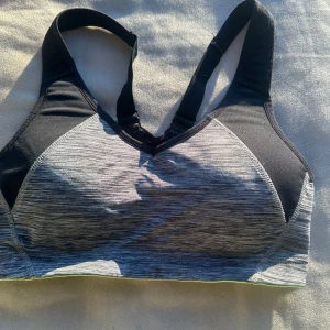 Grå och svart sport-bh från H&M - Säljer en grå och svart sport-bh från H&M. Den har breda axelband och en bekväm passform, perfekt för träning. Materialet är stretchigt och andas bra. Den har en justerbar rygg för optimal komfort.