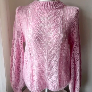Rosa stickad tröja - Säljer en söt rosa stickad tröja med ett vackert hålmönster. Tröjan har långa ärmar och en ribbad krage som ger en mysig känsla. Perfekt för kyligare dagar och att mysa i hemma. 💖Mohair