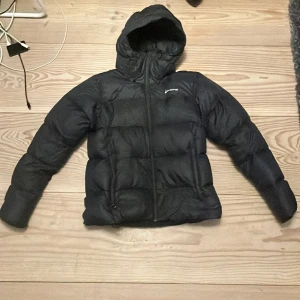 Svart dunjacka från Sail Racing - Säljer en svart dunjacka från Sail Racing i storlek medium men sitter som xs rekommenderar inte att köpa om man har medium men xs till small funkar. Jackan har en huva och dragkedja framtill. Perfekt för kalla dagar med sin pufferdesign som håller värmen.