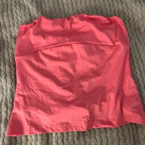 Rosa tubtopp - Säljer en snygg rosa tubtopp i bomull. Perfekt för sommardagar eller en festkväll. Toppen är i bra skick och har en enkel design. Passar perfekt till jeans eller kjol.
