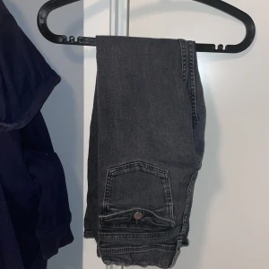 Svarta jeans från Gina Tricot - Snygga svarta jeans från Gina Tricot i storlek 152. De har en klassisk femficksdesign med knapp och dragkedja framtill. Perfekta för en stilren look.