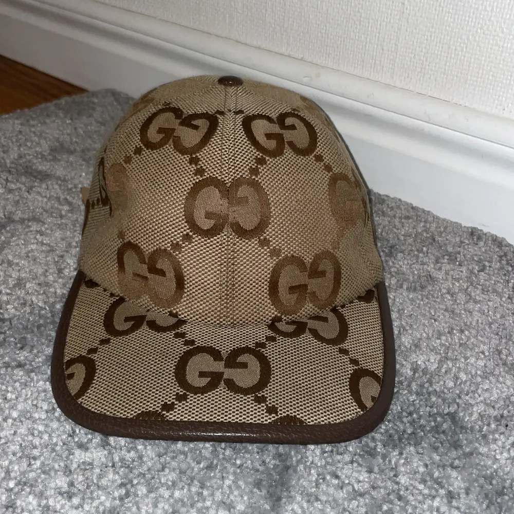 Snygg beige keps från Gucci med det ikoniska GG-mönstret i brunt. Kepsen har en justerbar rem baktill för perfekt passform. Perfekt för att ge din outfit en lyxig touch.. Accessoarer.