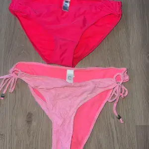 Säljer två snygga rosa bikinibyxor i olika nyanser. Den ena är starkt rosa och den andra ljusrosa med knytband i sidorna. Perfekta för sommarens strandhäng eller poolpartyn. Båda är i mycket bra skick och gjorda av ett mjukt och bekvämt material. Passar perfekt för en solig dag vid vattnet! 🌞