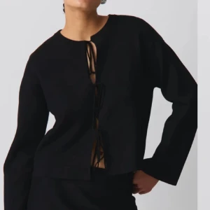 Svart tröja med snörning - Snygg svart tröja med cool snörning framtill. Perfekt för en stilren look, oavsett om du ska på fest eller bara vill känna dig extra chic. Tröjan har långa ärmar och en bekväm passform. Ett måste i garderoben för alla som älskar svart! Köpt på Plick men passade ej därför finns inga fler bilder! 