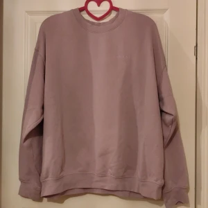 Ljuslila sweatshirt från Divided - Säljer en mysig ljuslila sweatshirt från Divided. Tröjan har en klassisk rund hals och långa ärmar, perfekt för en avslappnad stil. Den är i storlek M och passar utmärkt för kyligare dagar.