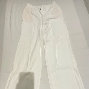 Vita byxor från FB Sister - Säljer ett par vita byxor från FB Sister i storlek L. Byxorna har en elastisk midja med knapp och dragkedja framtill. De har en loose passform och är perfekta för en avslappnad stil. Passar bra till alla tillfällen, ganska tunt material. Köpt på tjej avdelning men kan användas av båda könen.