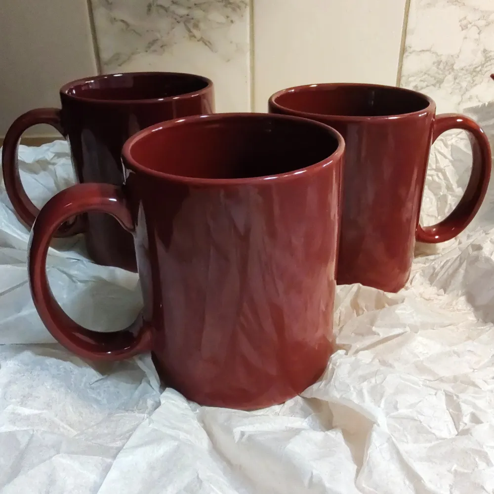 Säljer tre stilrena Vinröda muggar med ett stort handtag som är 8 cm långt. Varje mugg rymmer 4 dl, perfekt för kaffe eller te. Muggarna har en blank yta och en klassisk design som passar i alla kök. Perfekt nu till Jul/Nyår. 3st för 25:- Oanvända med prislappar kvar . Muu.