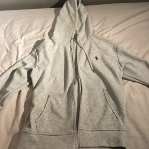 Ralph Lauren hoodie - Säljer en snygg och bekväm grå hoodie från Ralph Lauren. Den är knappt använd, bara ett fåtal gånger. Skick 9/10. Storlek S