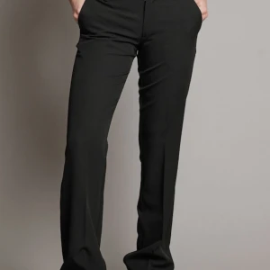 Svarta kostymbyxor - Snygga svarta kostymbyxor med låg midja och rak passform. Perfekta för en stilren look. Byxorna har en klassisk design med dragkedja och knapp framtill. Liten u storleken så skulle säga att den passar en S/M. 