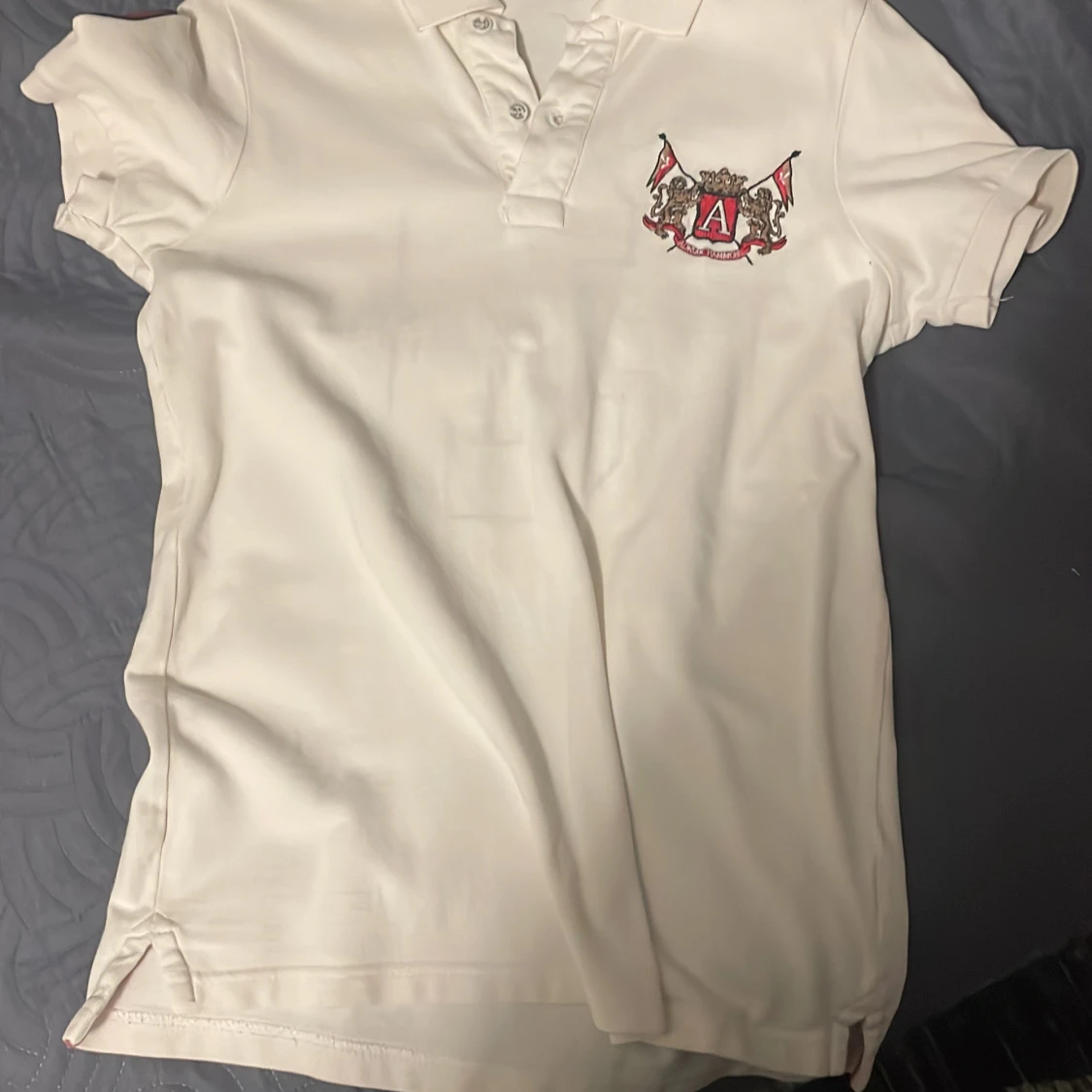 Vit pikétröja med emblem och nummer