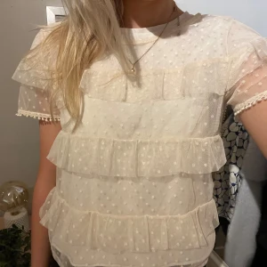 Vit topp  med volanger och prickigt mönster - Vit topp med korta ärmar och volanger 💘💘är genomskinlig men perfekt att ha en t-shirt eller linne under. Köpt secondhand. 