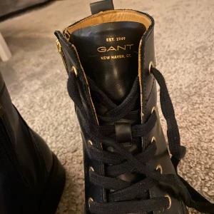 Svarta boots från Gant - Snygga svarta boots från Gant i skinn med snörning och dragkedja på sidan. Perfekta för höst och vinter med en stilren design och bekväm passform. De har en klassisk look som funkar både till vardags och fest. Storlek 39.