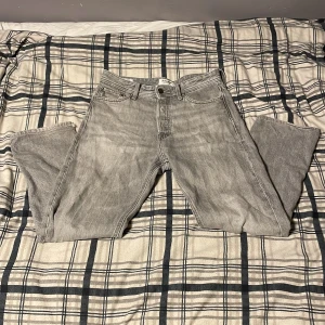 Grå jeans från Jack & Jones - Säljer ett par grå jeans från Jack & Jones i modellen Relaxed/Chris. De har en avslappnad passform och är i bra skick, men med lite slitage vid bensluten. Perfekta för en casual look! 🕶️W29 L30
