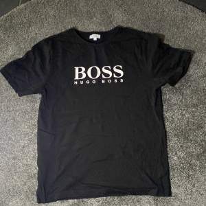 Säljer en stilren svart t-shirt från Hugo Boss i mycket bra skick. Den har en klassisk passform med korta ärmar och ett stort BOSS-tryck på framsidan. Perfekt för både vardag och fest! 🖤 köpt på kidsbrandstore 