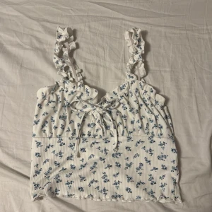 Vit blommig linne med volangdetaljer - Söt vit linne med blå blommor. Storlek M