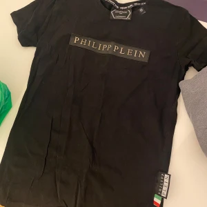 Svart t-shirt från Philipp Plein - Säljer en svart t-shirt från Philipp Plein . Den har en stilren design med märkesloggan tryckt på bröstet. Storlek M men skulle säga att den är mer som en storlek XS/S