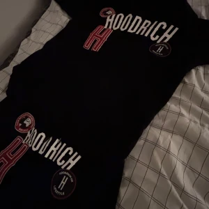 Svart hoodie och byxor från Hoodrich - Snygg svart hoodie och matchande byxor från Hoodrich med vita och röda detaljer. Setet har tryck med texten 'Hoodrich' och flera märken på både tröjan och byxorna. Perfekt för en avslappnad stil dressen är äkta och används inte perfekt nu för vintern, båda är M men byxorna passar även S, för mer info kontakta mig 