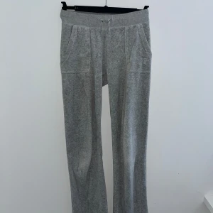 Gråa Juciy couture byxor - Gråa juciy couture byxor som är i bra skick. De har en liten fläck som knappt syns (bild 3) men annars inga defekter. Kan skicka bild på lappar och annat om de behövs. De är även i storlek xs och lite korta på mig som är 170 men inte mycket.