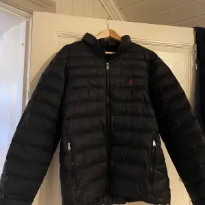 Säljer en snygg svart dunjacka från Ralph Lauren i storlek L. Det är en tunnare dunjacka så passar perfekt för vår och höst men funkar även på vintern. Jackan är i fint skick och äkta såklart, inga hål eller defekter. 