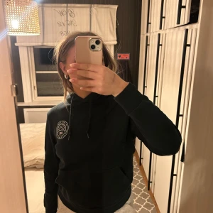 Mörkgrön hoodie från Dope - Säljer en svart hoodie från Dope med en stor logga på ryggen och en mindre på bröstet. Nyskick. Storlek 40