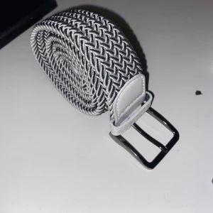 Flätat bälte - Flätat bälte med färgerna vit som grund färg sen svart lite smått prickig över som jag tycker är väldigt snyggt. Färgen passar alla jeans eftersom att den ör vit och svart. Perfekt för att stärka upp en outfit!