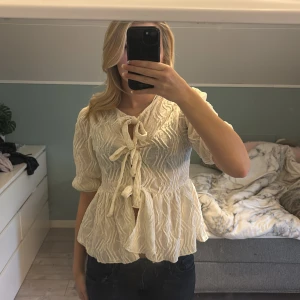 Blus - Kräm vit/gul blus från Gina. Den här fina detaljer och söta knytningar längs magen. Sälja då den aldrig används, köpt för 499kr men säljs för 350, pris kan diskuteras!!💞strolek S