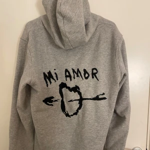 Grå hoodie med 'Mi Amor' tryck - Säljer min Mira Paris hoodie. Den är supermjuk och perfekt för kyliga dagar. Har en klassisk känguruficka och justerbar huva. Perfekt för en avslappnad stil!