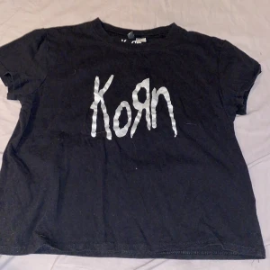 Svart Korn t-shirt från H&M Divided - Svart t-shirt från H&M Divided med Korn-logga i vitt på framsidan. T-shirten är kortärmad och gjord i mjukt bomullsmaterial. Passar perfekt till vardags.