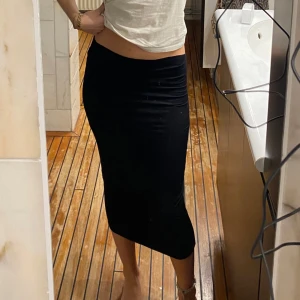 Svart tight kjol - Säljer en stilren svart tight kjol som passar perfekt för både vardag och fest. Kjolen är i ett mjukt och stretchigt material som formar sig snyggt efter kroppen. Den är knälång och har en enkel design utan detaljer, vilket gör den lätt att matcha med olika toppar och accessoarer. Perfekt för en chic och minimalistisk look!