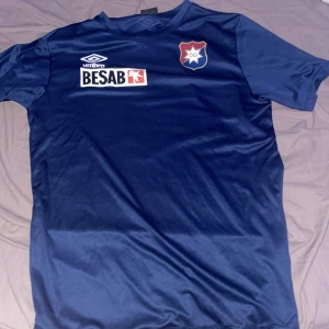 Örgryte Fotbollströja Umbro - Säljer en snygg blå Örgryte fotbollströja från Umbro i storlek L. Tröjan har korta ärmar och klubbmärket på bröstet. Perfekt för fotbollsfans eller träning! 🏆