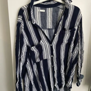 Randig skjorta i blått och vitt - Säljer en snygg randig skjorta i blått och vitt. Skjortan har långa ärmar och knappar framtill. Perfekt för både vardag och festliga tillfällen. Den är i mycket bra skick. Jätte fin till kostymbyxor eller blåa jeans men får ingen användning för den tyvärr 