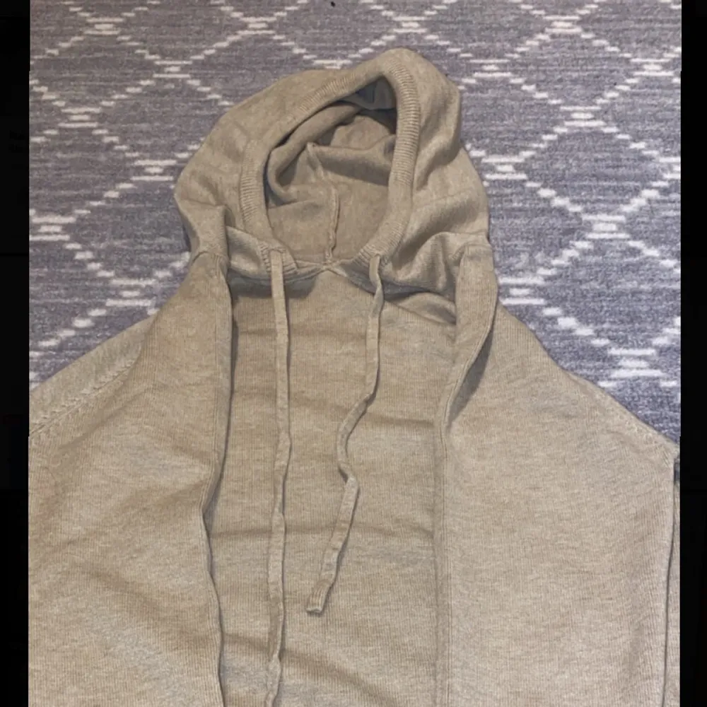 Säljer en helt oanvänd mysig beige hoodie i merinoull. Den har en klassisk design med dragsko i huvan och ribbade muddar vid ärmslut och nederkant. Perfekt för en avslappnad stil under höst och vår.. Tröjor & Koftor.