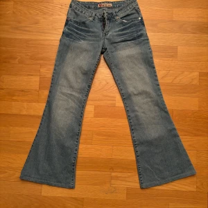 Låga jeans från Ying Zu - Säljer ett par snygga blå lågt skurna bootcut jeans från Ying Zu. De är i storlek XS skulle jag säga. Midja:34.5 Total längd: 91.5 Innerben: 71